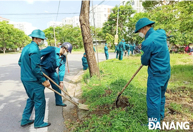 Lực lượng dân quân quận Sơn Trà dọn vệ sinh môi trường các bãi đất trống trên địa bàn phường Nại Hiên Đông.  Ảnh: CÁT TƯỜNG