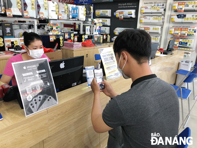 Khách hàng trải nghiệm hình thức thanh toán dịch vụ không tiền mặt tại tuyến phố Nguyễn Văn Linh - phố mua sắm không dùng tiền mặt của quận Hải Châu. Ảnh: DIỆP NHƯ