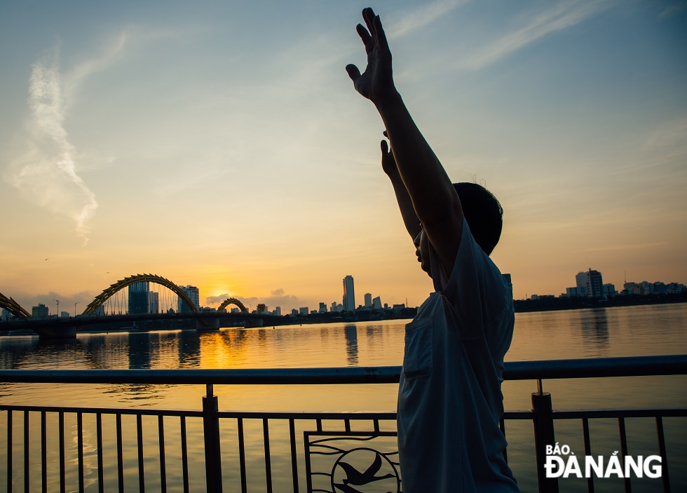 Người đàn ông vươn vai tập thẻ dục lúc sáng sớm ngay sát cầu Rồng - Biểu tượng của thành phố Đà Nẵng.