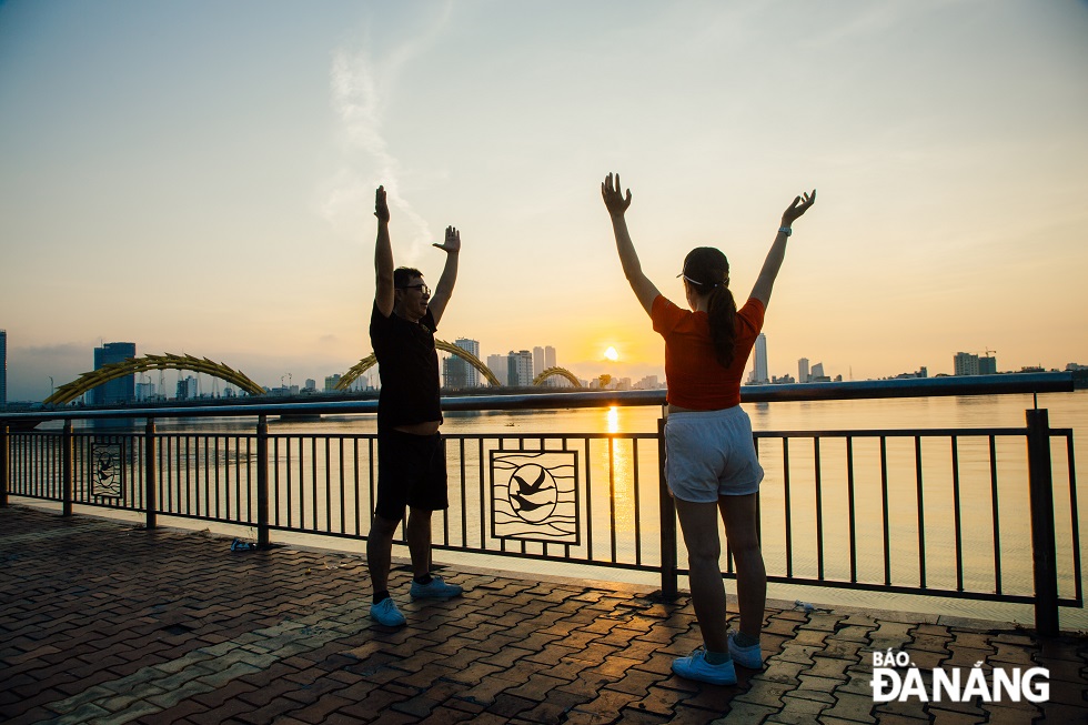 Two people doing physical morning exercisers on the Bach Dang Street riverside promenade