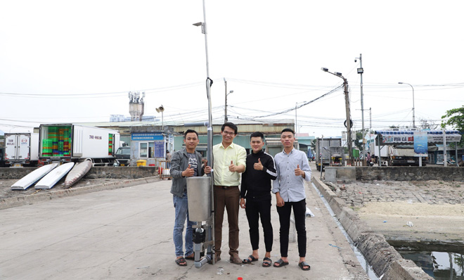 Master Tran Ngoc Son (second from left) along with automatic watersurface cleaning device creators and their invention at the the Tho Quang Fishing Wharf.