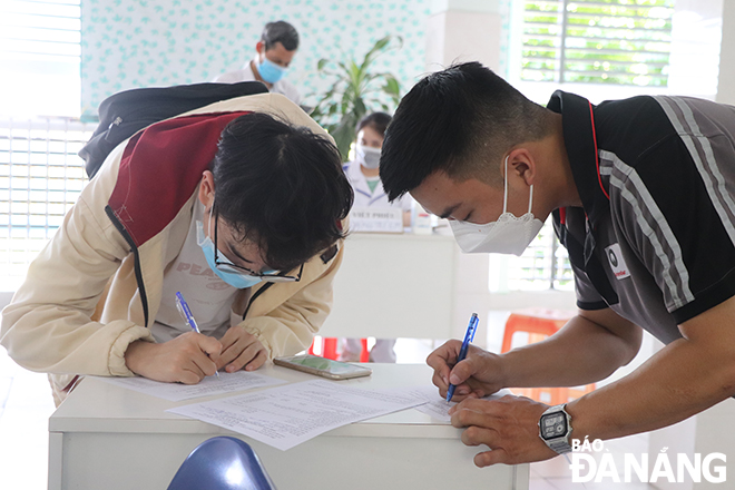 Người dân đến Trung tâm Y tế quận Sơn Trà (cơ sở 2) điền thông tin để khám sàng lọc và tiêm vắc-xin mũi 4.
