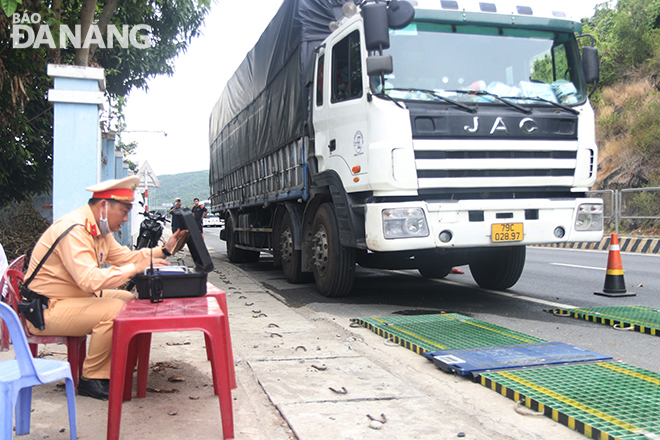 On the first day of the operation, traffic police officers at Hoa Hiep Gate pull over series of vehicles to check their load.