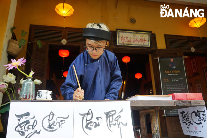 Võ Tuấn Xuân Thành viết thư pháp tại triển lãm “Hoài niệm phố Hội”.  Ảnh: XUÂN SƠN