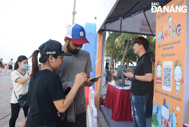 A large number of people and tourists enjoy the culinary flavours and shop for Da Nang’s typical souvenir products. A foreign visitor is seen scanning the QR code to receive the gift voucher.