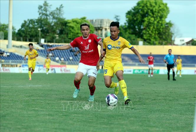 Pha tranh chấp bóng giữa cầu thủ Sông Lam Nghệ An (áo vàng) và cầu thủ Thành phố Hồ Chí Minh (áo đỏ). Ảnh: TTXVN phát