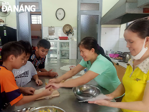 Ms Nguyen Thi Chin and Ms Nguyen Thi Kim Oanh (right ) cook with their children. Photo: PHUONG MINH