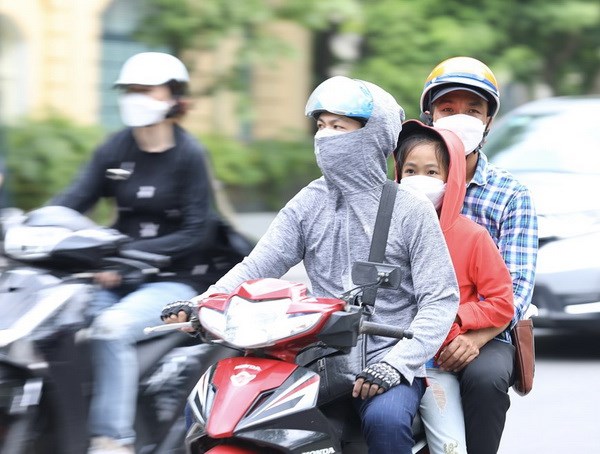 Người dân mặc đồ kín mít tránh nắng, nóng khi phải di chuyển trên đường. (Ảnh: Hoàng Hiếu/TTXVN)
