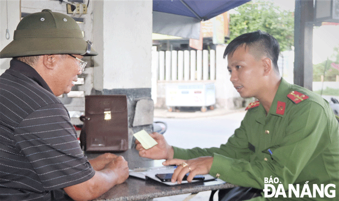 Thượng úy Phạm Hoàng Anh Khoa (bên phải) và ông Nguyễn Giỏi, Tổ trưởng tổ dân phố số 123, phường Hòa Minh trao đổi thông tin về tình hình an ninh trật tự trên địa bàn. Ảnh: ĐẮC MẠNH	