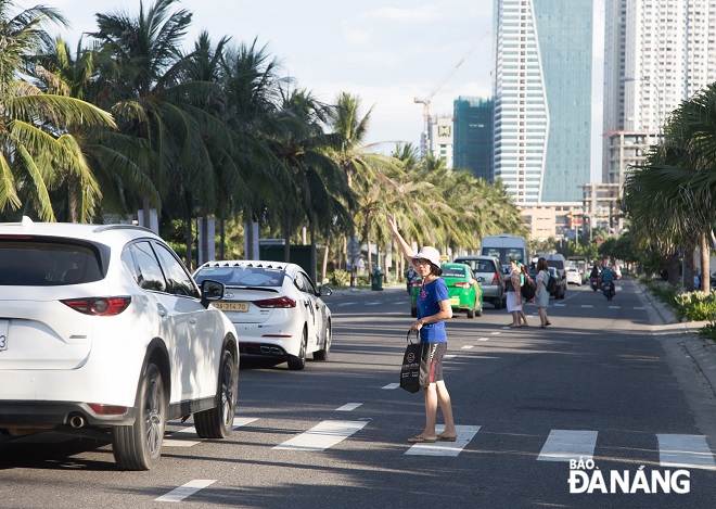 A woman raising her hand when crossing the street. Photo: CHANH LAM