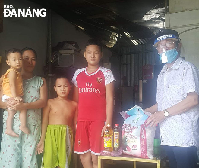 Ông Nguyễn Tiến Dân (bìa phải) trao quà cho gia đình khó khăn ở quận Thanh Khê. Ảnh: MỸ VÂN