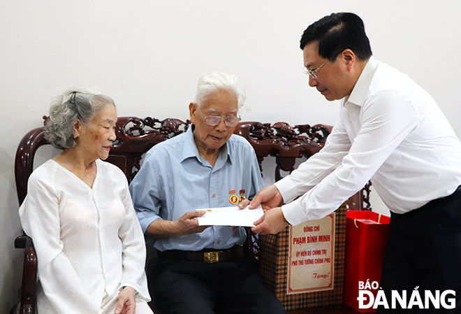 Permanent Deputy Prime Minister Pham Binh Minh (right) presenting a gift to war invalid Thai Phuoc Hiep