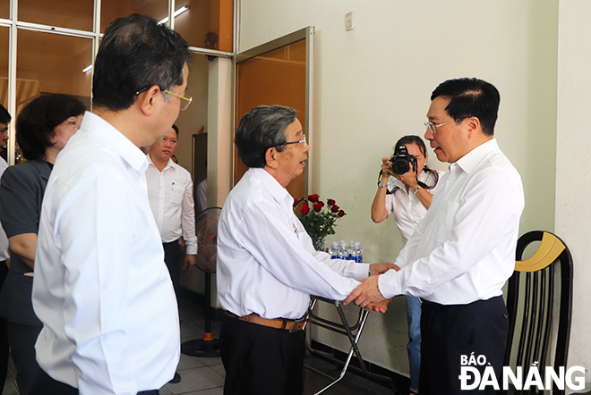 Permanent Deputy Prime Minister Pham Binh Minh (right) extending his good health wishes to Mr. Do Minh Chung - a son of a martyr.  
