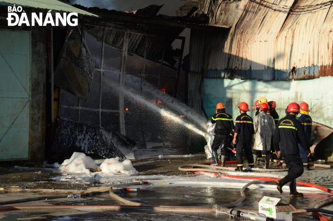 Fire crews are at the scene of the large warehouse blaze on Hoang Van Thai Street. Photo: NGOC QUOC.