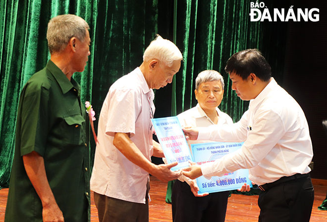 Phó Bí thư Thường trực Thành ủy, Chủ tịch HĐND thành phố Lương Nguyễn Minh Triết trao tiền hỗ trợ cho các gia đình chính sách. Ảnh: XUÂN DŨNG         