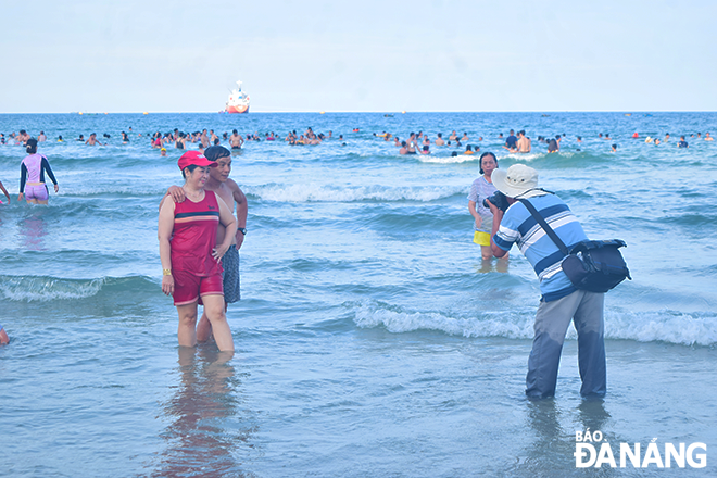 Mr. Muoi is taking photos of his customers on the My Khe beach. Photo: THU DUYEN