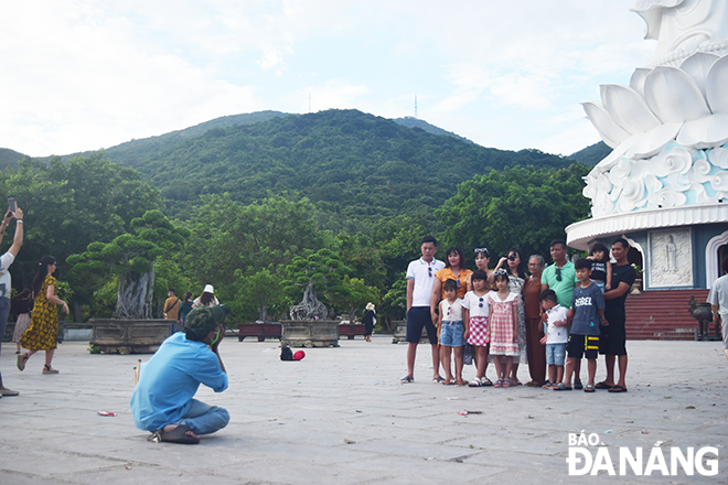Mr. Them is taking photos of his customers at the Linh Ung Pagoda. Photo: THU DUYEN