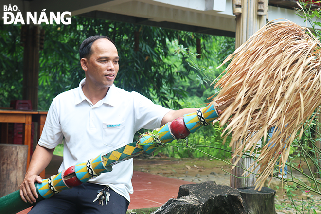 Secretary of Gian Bi Village Party Organisation Dinh Van Nhu taking care of a bamboo pole model which is a distinctive feature of the Co Tu ethnic group. Photo: T.Y