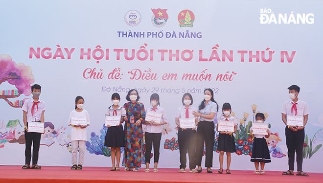 Chủ tịch Hội Từ thiện và Bảo vệ quyền trẻ em thành phố Lê Thị Tám (thứ 4, bên trái sang) trao bảng hỗ trợ chương trình “Mẹ đỡ đầu” cho các trẻ em mồ côi do hội đỡ đầu tại Ngày hội tuổi thơ năm 2022. Ảnh: LÊ VĂN THƠM