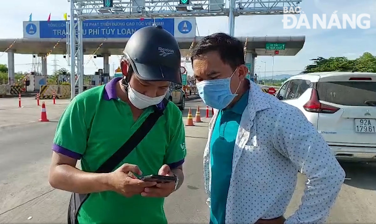 A vehicle driver asking for help from the service provider to check his account after the ETC system do not allow him to pass the toll booth because of not enough money in their his account to cover road tolls. Photo: PHUONG UYEN.