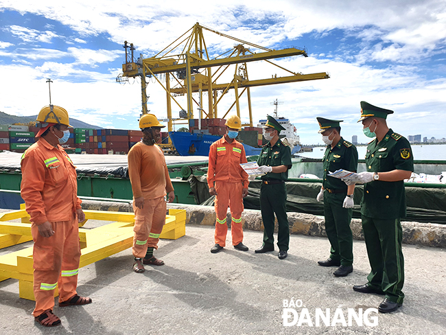 Cán bộ, chiến sĩ Trạm Biên phòng cửa khẩu cảng Tiên Sa (bên phải) tuyên truyền về phòng, chống dịch cho thuyền viên. Ảnh: DOÃN QUANG
