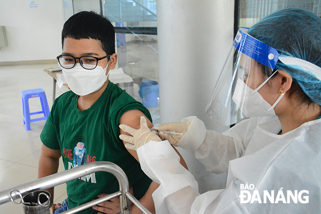 A medical professional giving a COVID-19 vaccine to a school pupil in Hai Chau District. Photo: PHAN CHUNG