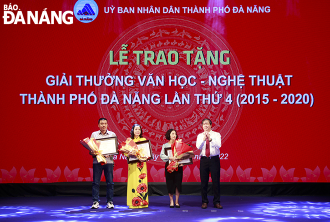Chủ tịch Liên hiệp các Hội Văn học - Nghệ thuật thành phố Bùi Văn Tiếng trao giấy chứng nhận giải thưởng và tặng hoa cho thân nhân gia đình cố tác giả có tác phẩm đoạt giải. Ảnh: XUÂN DŨNG