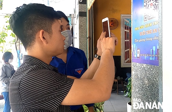  Mr. Le The Vinh, the owner of the 1997café, scanning the QR code to access digital library. Photo: TRUONG KY