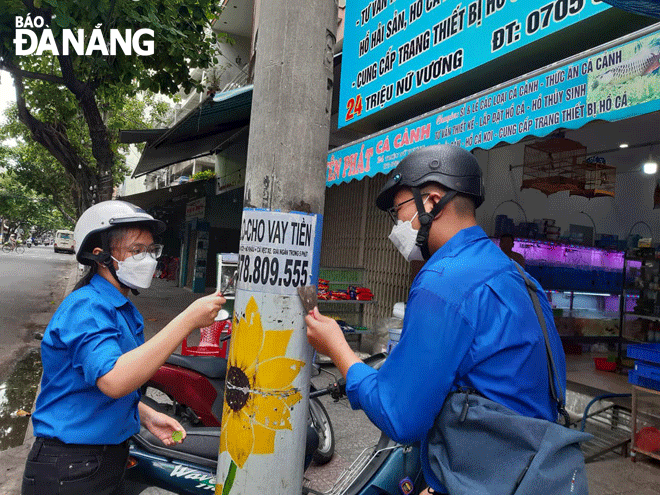 Đoàn viên, thanh niên quận Hải Châu ra quân tẩy xóa quảng cáo, rao vặt trái phép tại đường Triệu Nữ Vương. Ảnh: NGỌC QUỐC