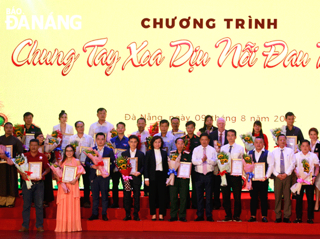 Phó Bí thư Thường trực Thành ủy Lương Nguyễn Minh Triết (thứ 6, từ phải sang) và Phó Chủ tịch UBND thành phố Ngô Thị Kim Yến (thứ 8, từ phải sang) tri ân và tặng hoa cho các đơn vị, tổ chức ủng hộ nạn nhân chất độc da cam trong những năm qua. Ảnh: XUÂN DŨNG