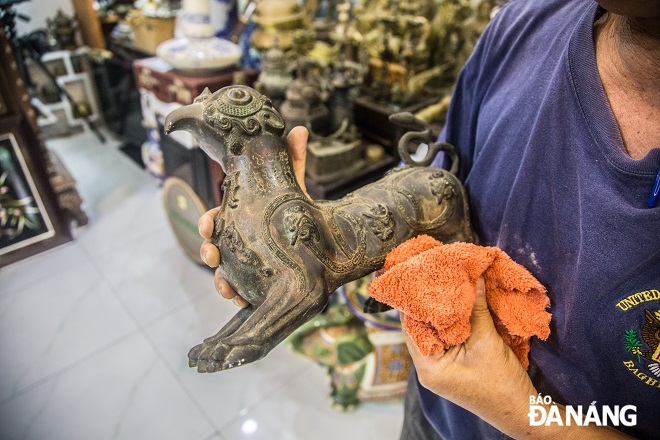 A bronze statue of a mascot engraved with Han script and other antiques are preserved very carefully by him