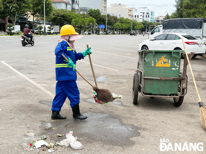 Chị Từ Thị Thông dọn vệ sinh môi trường trên tuyến đường Nguyễn Tất Thành (quận Thanh Khê). Ảnh: DIỆP NHƯ