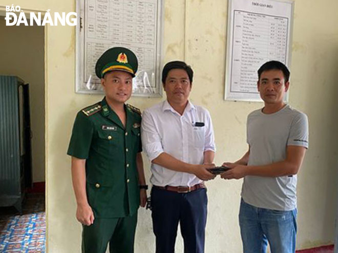 Mr. Truong Van Hoang (second, left) receiving his lost property. Photo: HONG QUANG