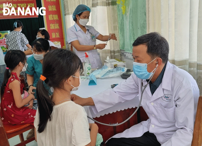 Học sinh tại xã Hòa Tiến được thăm khám sàng lọc trước khi tiêm vắc-xin phòng Covid-19.  Ảnh: NGỌC QUỐC	