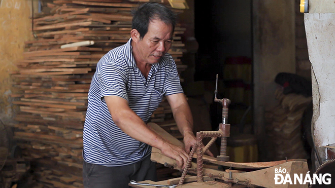 A craftsman is making a frame of a drum