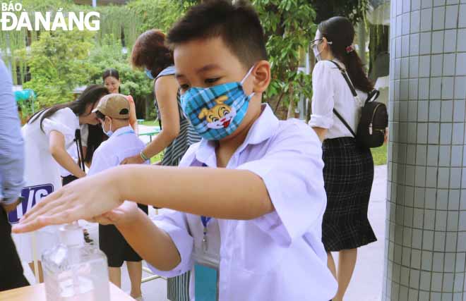 First graders are instructed to disinfect their hands before entering class. Photo taken at the Ly Tu Trong Primary School based in Hai Chau District.