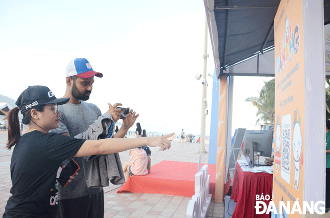 A staff member of the Da Nang Tourism Promotion Center (left) helping a foreigner to access information about the city’s events. Photo: NHAT HA