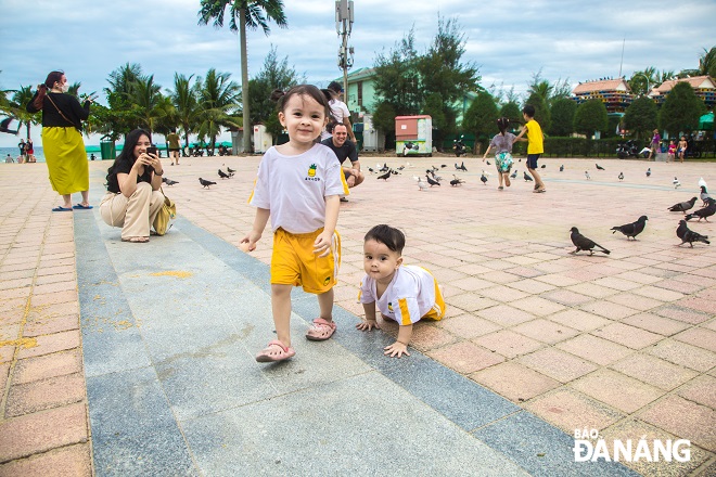 Hai đứa trẻ tỏ ra thích thú khi chơi đùa với những chú chim bồ câu tại công viên Biển Đông.