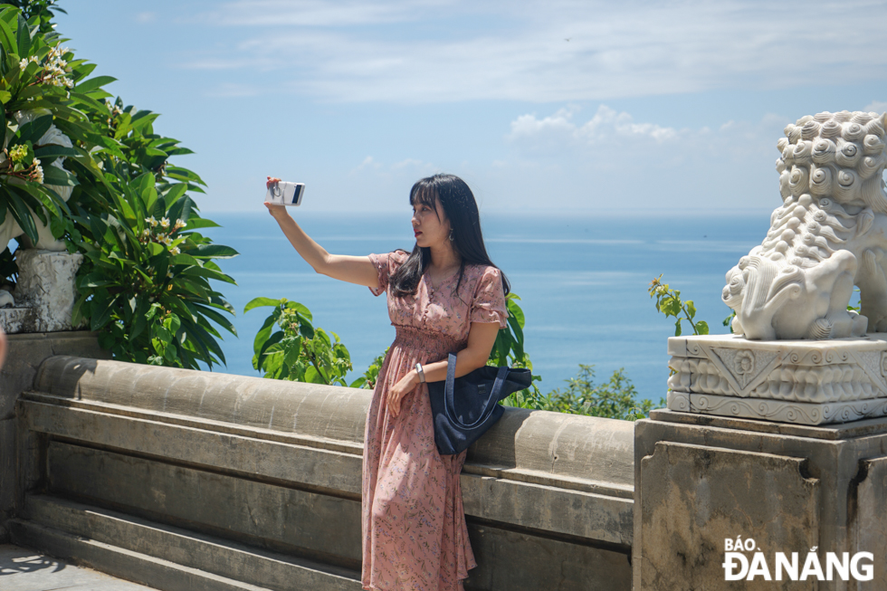 A tourist from South Korea taking souvenir pictures with the Son Tra Peninsula.