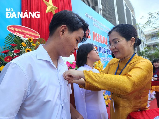 A school teachers attaching name tags to 10th graders at the Phan Chau Trinh Senior High School. Photo: PHAN CHUNG