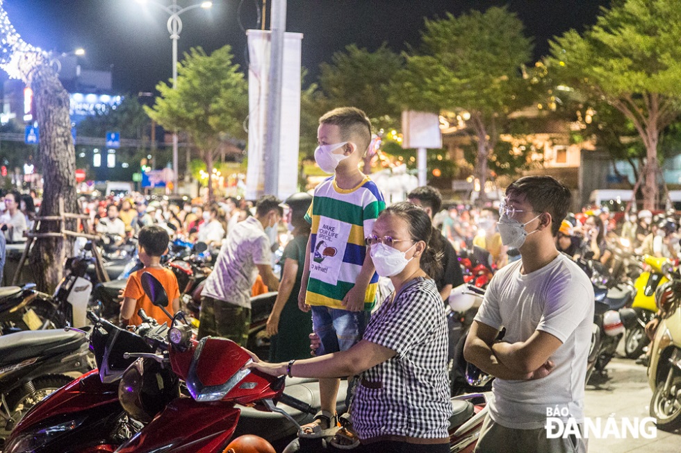 The mother lets her son stand on the motorcycle seat to see lion dance performances more clearly.