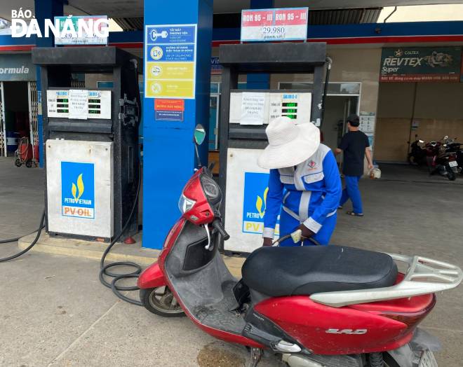 A motorcyclist has her vehicle re-filled at the filling station on Ngo Quyen Street in Son Tra District. Photo: QUYNH TRANG