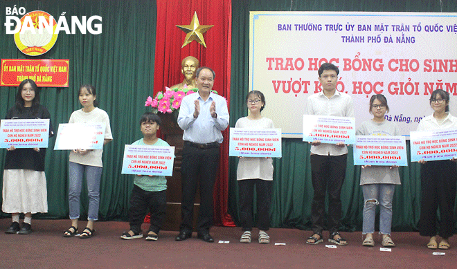 Da Nang Fatherland Front Committee Vice Chairman Duong Dinh Lieu awarding scholarships to poor pupils who achieved good learning outcomes in the 2021/22 academic year. Photo: X.HAU