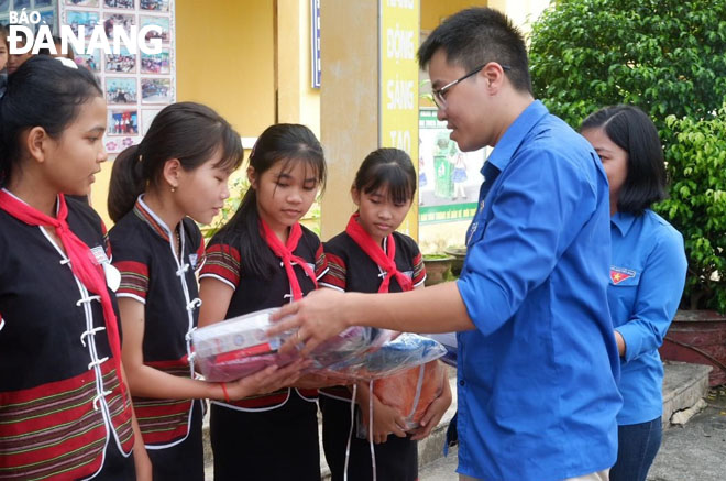 Doctor Phan Duc Tri (right) presents gifts to disadvantaged children in the Hoa Vang district. Photo: THAO NGUYEN