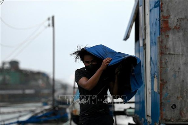 A man holds onto an umbrella to prevent it from being blown away by strong winds in Baseco, Philippines, on September 25, 2022. (Photo: AFP/VNA)