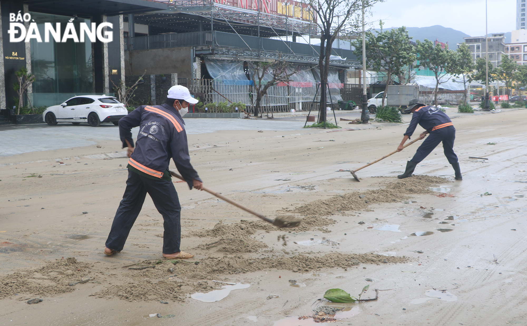 Workers of the Road Management Enterprise and the Da Nang Bridge and Road JSC came out to clear sea sand that spilled onto the roadway. Photo: VAN HOANG