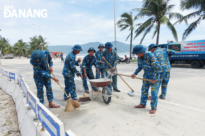 Các cán bộ, chiến sĩ quân đội tham gia thu dọn cát, vệ sinh tuyến đường Võ Nguyên Giáp. Ảnh: HOÀNG HIỆP