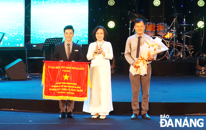 Vice Chairman of the Da Nang People's Committee Ngo Thi Kim Yen (middle) presenting the Emulation Flag to the Trung Vuong Theatre. Photo: XUAN DUNG