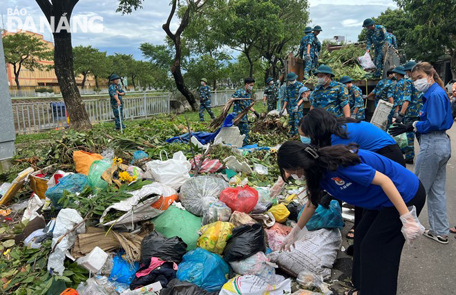 Đoàn viên thanh niên các địa phương và cán bộ, chiến sĩ các lực lượng vũ trang cũng tham gia thu gom rác và cành, lá cây gãy, rụng từ các điểm tập kết lên xe ben để vận chuyển lên bãi rác Khánh Sơn.