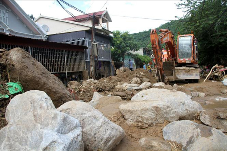 Lực lượng chức năng phải huy động nhiều máy móc để thu gom đất đá tại thị trấn Mường Xén, huyện Kỳ Sơn (Nghệ An) sau mưa lũ. Ảnh: Văn Tý/TTXVN.